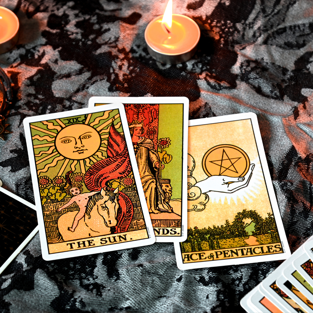 Tarot cards with The Sun and Ace of Pentacles displayed with a lit candle
